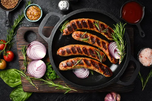 Izgarada, tavada pişmiş sulu sığır eti sosisi. Kapatın. Üst görünüm.