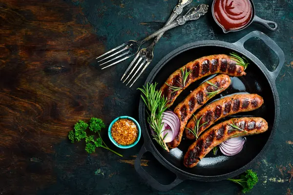 Izgarada, tavada pişmiş sulu sığır eti sosisi. Kapatın. Üst görünüm.