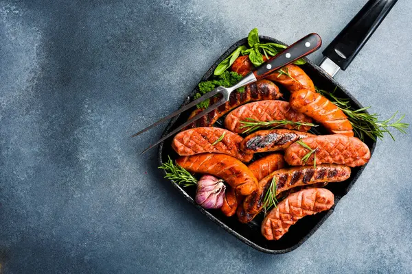 Metal ızgarada domuz eti, biftek ve tavuk sosisi. Üst görünüm, metin için boş alan.