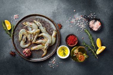 Taze çiğ karides, limon, tuz ve baharatlı karides. Gri bir arkaplanda.