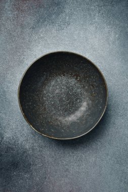 Seramik koyu yuvarlak desenli tabak. Gri beton arkaplanı kapatın. Metin için boş alan.