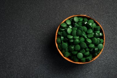 Kasedeki yeşil spirulina haplarını kapat. Koyu beton bir arka planda.