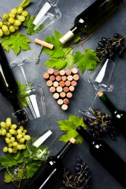 Taş bir masanın üzerinde şarap şişeleri, bardaklar, üzümler ve üzüm yapraklarının bileşimi. Üst Manzara. Metin için boş alan.