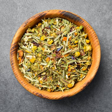 Tahta bir kasede kurutulmuş sağlıklı bitki çayı. Taş zeminde. Yakın plan..