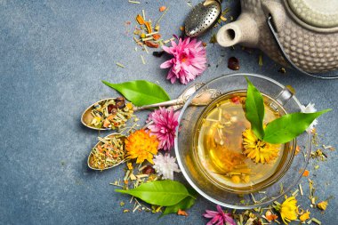 Sağlıklı bir fincan bitki çayı, kuru çay ve çiçekli kompozisyon. Gri beton arka planda. Dikey fotoğraf.