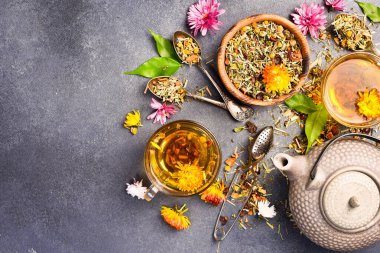 Bir fincan çay, bir çaydanlık ve bir demet aromatik çiçek çayıyla kompozisyon. Metin için boş alan.