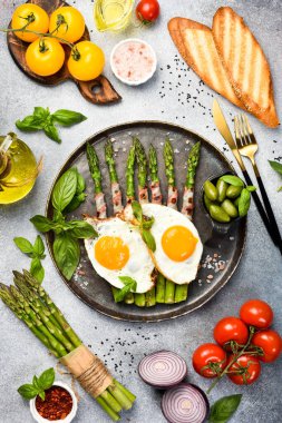 Faydalı bir kahvaltı. Kızarmış kuşkonmaz, pastırma ve kızarmış yumurta tabağı. Üst görünüm.