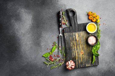 Gri taş pişirme arka planı. Mutfak kesim tahtası, baharatlar ve sebzeler. Üst Manzara. Metnin için boş yer.