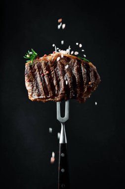 Biberiyeli biftek ve çatallı baharat. Izgara biftek. Siyah bir arkaplanda.