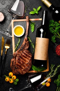 Şişe şarap, bardaklar ve biftek. Siyah Angus bifteği ve yıllanmış şarap. Üst görünüm.