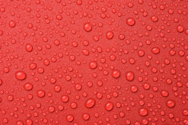 Kırmızı zemine su damlıyor. Tasarım veya metin için desenli yüzey. Üst Manzara. Boş alan.