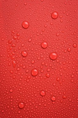 Kırmızı arka planda su damlalarının makro fotoğrafı. Dikey fotoğraf. Üst görünüm.