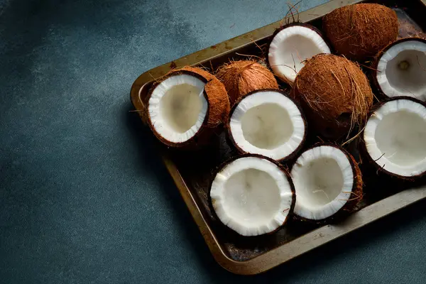 Metal bir tepside taze hindistan cevizleri. Tropik fındıklar yakın plan. Karanlık bir arka planda.