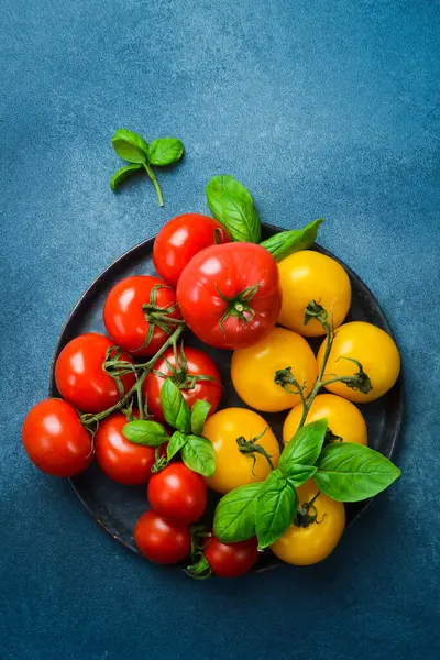 Siyah taş tabakta taze organik domatesler. Üst görünüm.