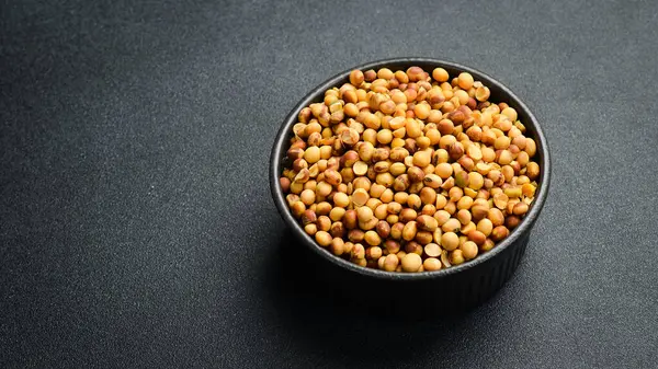 Soya fasulyeli siyah taş kâse. Kuru fasulye tohumu. Siyah taştan bir arka planda.
