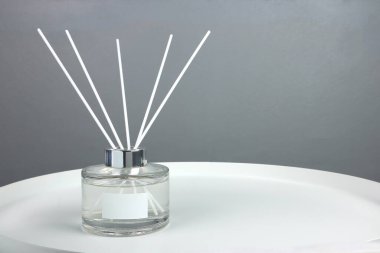Lüks kokulu kamış kokusu yayıcı cam şişe beyaz etiketli beyaz çelik masanın üzerinde romantik yaratmak ve yatak odasındaki ortamı gevşetmek için öğleden sonra gri duvar arkaplanlı.