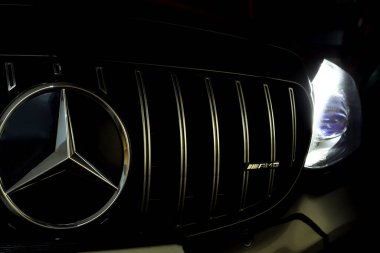 Mercedes Benz krom ızgara Benz yıldızı ve siyah c sınıfı AMG coupe modeliyle amg logosu servis kontrolü sırasında karanlık garajda.