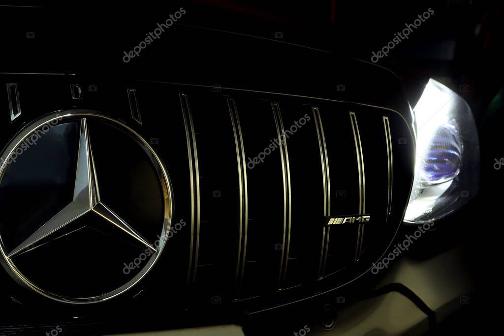 Mercedes Benz chromium grille with Benz star and amg logo with led headlight of black c class c200 coupe AMG model in the dark garage during maintainance checking service