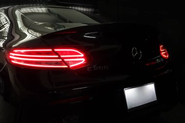 Siyah spor araba markası Mercedes Benz c200 Coupe 'nin arka lambası kontrol ve bakım süresince garajda bırakılmış.
