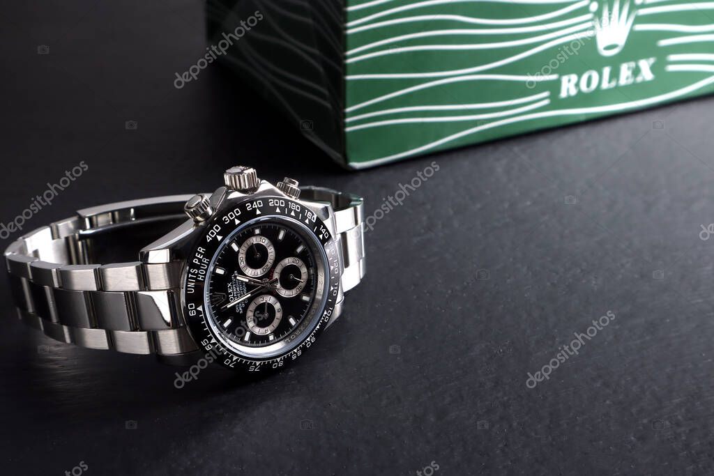 Rolex wristwatch model cosmograph daytona oyster perpetual superlative chronometer with black ceramic bezel stainless steel body display on black wooden table in authorized dealer shop