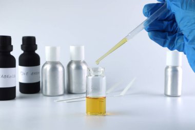 chemical beaker , flask is on white table with blotting paper , fragrance bottle and essential oil bottle are used to blend the nice scent for making perfume and candle by perfumer in the laboratory