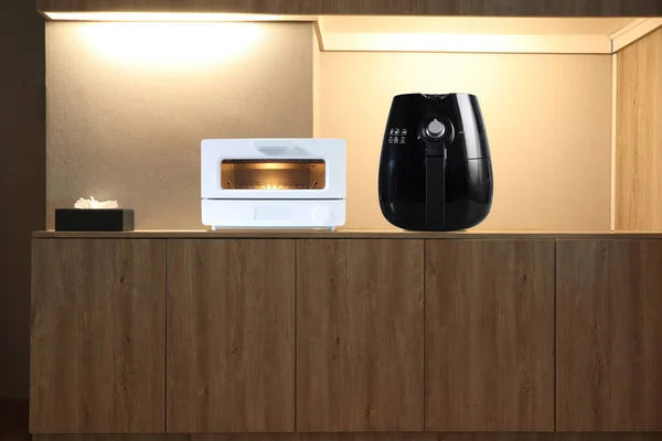 white modern design toaster oven and black air fryer are on the brown wooden table in the nice dinner kitchen room during breakfast