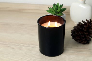 Aromatik kokulu mum, lüks siyah cam bardakta ve küçük kaktüs, aile üyeleriyle Noel partisi sırasında minimum zen tasarım yatak odasındaki ahşap masada sergilenir.