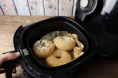 Ev yapımı organik bagel ekmekleri, ahşap masa ve duvar altyapısı ile işe gitmeden önce sabah kahvaltısı olarak siyah hava fritözü veya yağsız fritöz kullanılarak pişirilir.