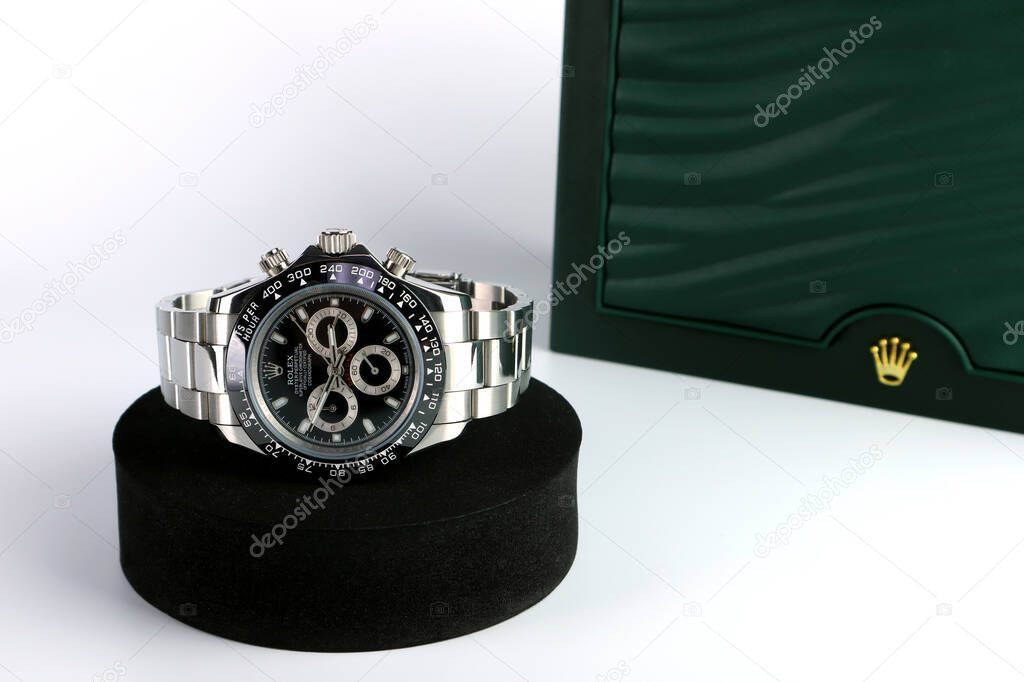 Rolex wristwatch model daytona oyster perpetual with black ceramic bezel stainless steel body displayed on white table with Rolex signature green box in the authorized distributor shop