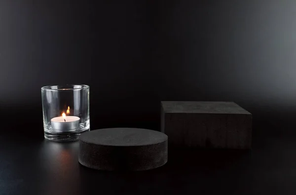black cylinder podium or display stand, scented aromatic tealight candle in nice glass. Black cement wall scene mockup product display. Abstract geometric platforms. Round stage for showcase