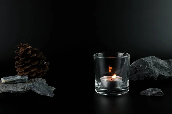 aromatic scented tealight candle glass is on black table with many stones and background of black wall of house in bed room to creat relax and romantic moment for lovers on Valentine day