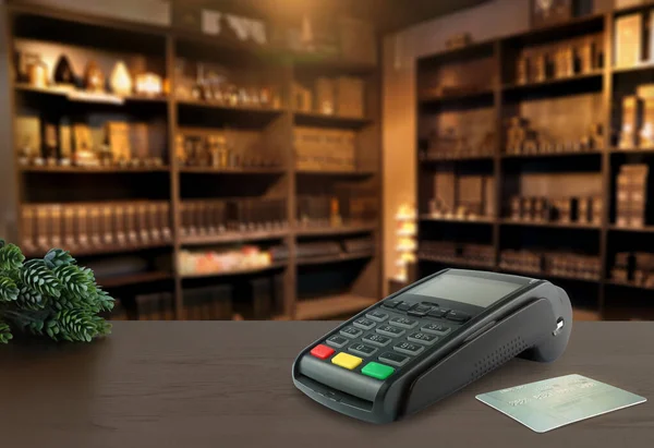 credit card reader pos machine and a credit card are on the wooden table with background in the home aromatic fragrance products retail shop