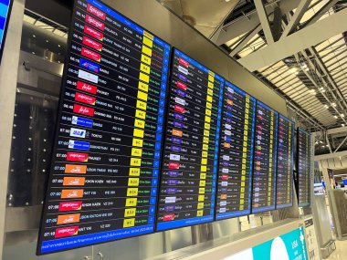 Uçuş durumu ekranında Suvarnabhumi Havaalanı terminalindeki yolcuların varış saati, gecikme, kapı numarası, havayolu, varış yeri ve uçuş numarası gösteriliyor.