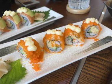 Suşi somon rulosu, Sashimi somonu, Japon restoranında ahşap masada, yeni yıl partisinde ailesiyle yemek yerken.