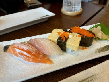 Birçok lezzetli suşi, suşi somon rulosu, saşimi somon balığı Japon restoranındaki ahşap masada yeni yıl partisi günü ailesiyle birlikte akşam yemeği sırasında tabakta.
