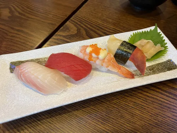many kinds of delicious sushi , sushi salmon roll , sashimi salmon are in plate on wooden table in Japanese restaurant during dinner with family on New Year party celebration day