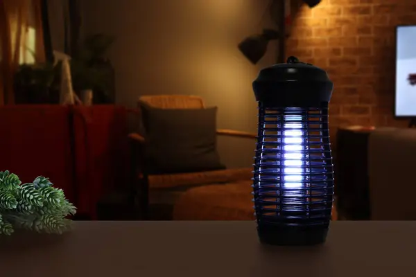an insects mosquito electric blue light killer lamp is put on the black wooden table in the nice livingroom with background of tv and sofa to protect the mosquito during relax time