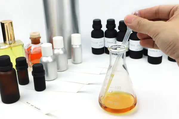 stock image chemical beaker , flask is on white table with blotting paper , fragrance bottle and essential oil bottle are used to blend the nice scent for making perfume and candle by perfumer in the laboratory