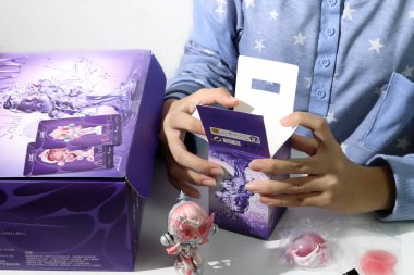 Skullpanda 'nın şirin sanat oyuncakları kutusu Pop Mart' ın kör kutu koleksiyonu toplanabilir şirin oyuncaklar beyaz masadaki çocuklar tarafından güzel bir tasarım kutusu ve gri duvar arka planlı kartlarla açılıyor.