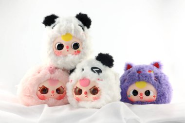 Dört sevimli pofuduk oyuncak karakter, Bebek Üç büyük, peluş bebek serisi peluş bebekler Çin 'den gelen gizemli kutu markalı bebek üç, beyaz masada sergileniyor oyuncakçı dükkanındaki beyaz duvarın arka planında.