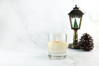 Aromatik kokulu cam mum ve Noel süslemeleri yatak odasındaki beyaz mermer masada sergilenir. Mutlu Noeller gününde ortam rahatlasın diye.