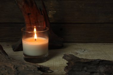 Yeni yıl kutlamaları sırasında rahatlamak için oturma odasındaki eski ahşap kulübe duvarının arka planında bulunan ahşap masa üzerinde lüks kokulu mum camı yakmak.