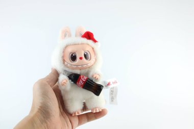 Sanat oyuncakları Labubu anahtarlık koleksiyonu Pop Mart 'ın kör kutusundan toplanabilir sevimli oyuncaklar yeni çıkan Coca Cola labubu macaron bebek albümünde Pop Mart bayrak mağazasının beyaz raf arka planında sergileniyor.