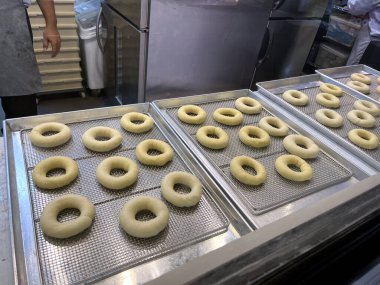 Lezzetli çörekler, Noel festivali ekmek indirimi sırasında müşterilere satılmadan önce donat fırınındaki büyük paslanmaz fırının arka planında mutfak tepsilerinde hazırlanır ve pişirilir.
