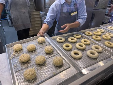 Lezzetli çörekler, Noel festivali ekmek indirimi sırasında müşterilere satılmadan önce donat fırınındaki büyük paslanmaz fırının arka planında mutfak tepsilerinde hazırlanır ve pişirilir.
