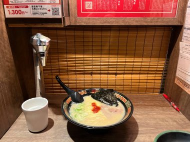 Tokyo Japonya 9 Mayıs 2025, bir kase lezzetli Ichiran ramen, ahşap masa üzerinde bir bardak su ve ahşap perde ve Ichiran Ramen dükkanında menü, ünlü eşsiz tonkotsu çorbası ramen lezzetli