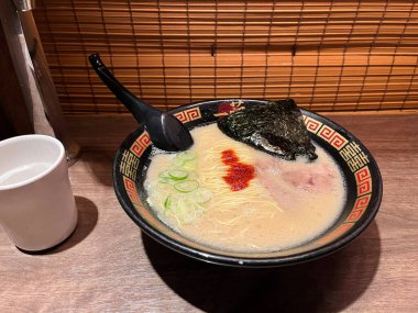 Tokyo Japonya 9 Mayıs 2025, bir kase lezzetli Ichiran ramen, ahşap masa üzerinde bir bardak su ve ahşap perde ve Ichiran Ramen dükkanında menü, ünlü eşsiz tonkotsu çorbası ramen lezzetli
