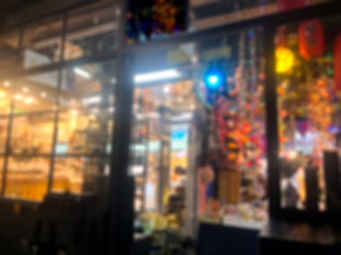 Dekorasyon partisinin bulanık fotoğrafı ışık toplarına öncülük etti. Elektrikçilerin önünde süslenmiş güzel bir şekilde gece vakti markette siyah cam pencerelerden yılbaşı kutlamalarına baktı.