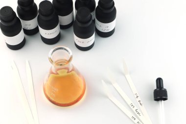 Kimyasal deney şişesi, beyaz masada kurutma kağıdı, parfüm şişesi ve esaslı yağ şişesiyle parfüm yapımında kullanılıyor. Laboratuvarda parfüm üreticisi tarafından sazlık dağıtıcısı kullanılıyor.