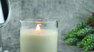 Güzel, yanan, lüks kokulu mum camı, Sevgililer Günü 'nde sevgililer için rahat ve romantik bir an yaratmak için yatak odasındaki gri taş duvarın arka planında, taş masanın üzerinde duruyor.